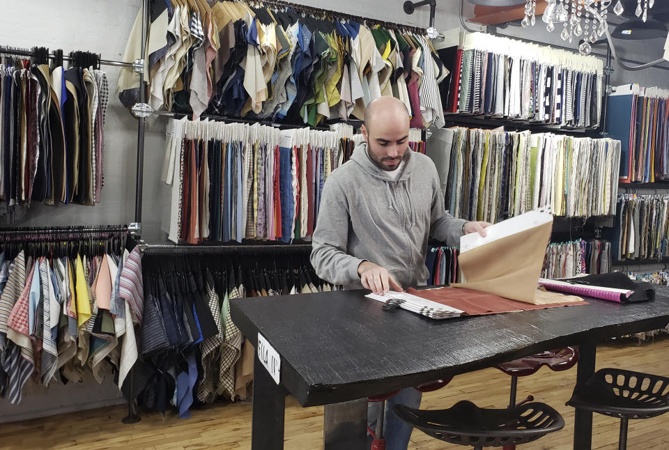 In this March 11, 2020 photo, Giovanni Belotti, looks at materials on a table at FB LP Textiles Inc., in New York City. Belotti is an Italian ex-pat living in New York City. Italians in New York are worried for loved ones in Italy who are living under a nationwide lockdown to stem the spread of the new coronavirus. For most people, the new coronavirus causes only mild or moderate symptoms. For some it can cause more severe illness.(AP Photo/Deepti Hajela)