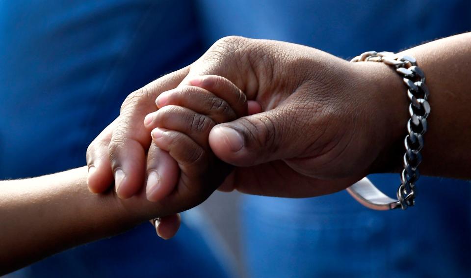 Mother and son now: Josiah Carles Turner, age 2, holds hands with his mom, Chekinaa Turner. The two were united as family during a  "Celebration of Adoption" at the USSSA Space Coast Complex stadium. Judge Kelly McKibben conducted the ceremony, during which 10 families adopted 12 children.