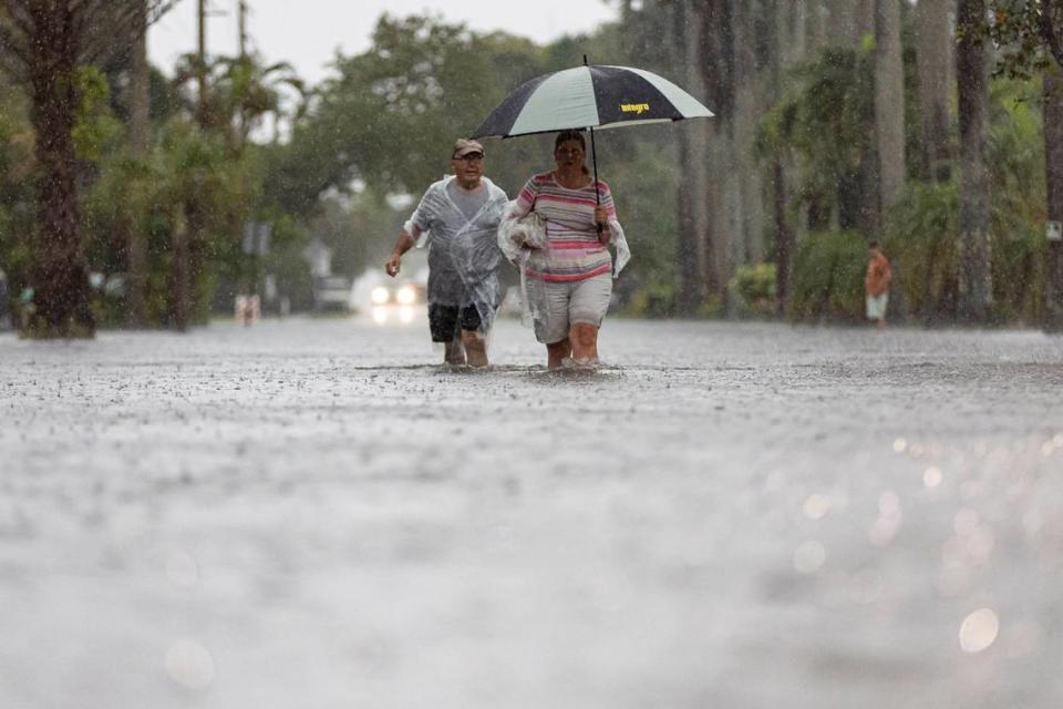 Jim Comunale y Pam Mervos caminan por Arthur Street mientras las fuertes lluvias inundan el vecindario circundante el miércoles 12 de junio de 2024 en Hollywood, Florida.