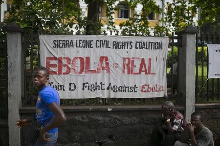 A man walks past a banner about Ebola in Freetown, Sierra Leone, December 16, 2014. REUTERS/Baz Ratner