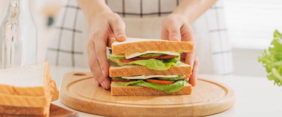 Person holding sandwich on cutting board