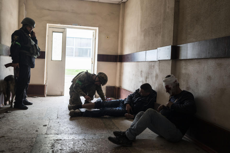 A member of security forces gives first aid to an injured man following a Russian bombing of a factory in Kramatorsk, eastern Ukraine, Tuesday, April 19, 2022, killing at least one person and injuring three others. Russian forces attacked along a broad front in eastern Ukraine on Tuesday as part of a full-scale ground offensive to take control of the country's eastern industrial heartland in what Ukrainian officials called a "new phase of the war." (AP Photo/Petros Giannakouris)