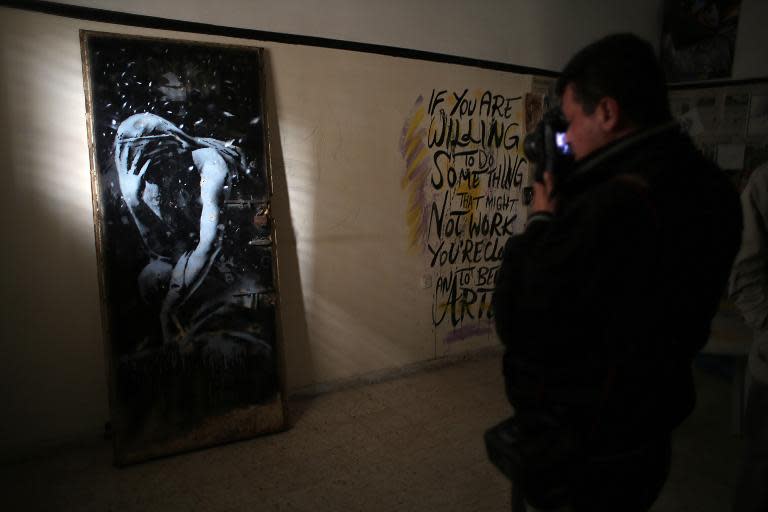 A photographer takes a picture of a mural of a weeping woman, said to have been painted by British street artist Banksy, in Khan Yunis on April 1, 2015