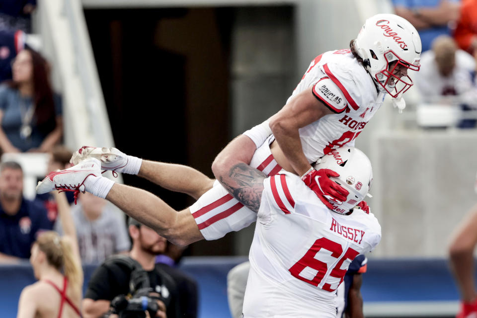 FILE - Houston wide receiver Jake Herslow (87) celebrates with offensive lineman Kody Russey (65) after scoring the go ahead touchdown against Auburn during the second half of the Birmingham Bowl NCAA college football game Tuesday, Dec. 28, 2021, in Birmingham, Ala. Cincinnati, Houston and Central Florida will depart the American Athletic Association for the Big 12 next year. Not surprisingly, those teams are picked to again finish atop the AAC before they leave. (AP Photo/Butch Dill, File)