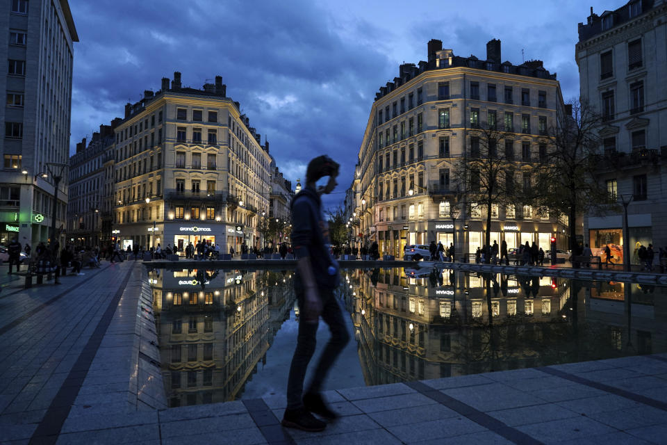 A man wearing a mask walks in the street in the center of Lyon, central France, Wednesday, Oct. 28, 2020. France is bracing for a potential new lockdown as the president prepares a televised address Wednesday aimed at stopping a fast-rising tide of virus patients filling French hospitals and a growing daily death toll. French markets opened lower on expectations that President Emmanuel Macron will announce some kind of lockdown Wednesday. (AP Photo/Laurent Cipriani)