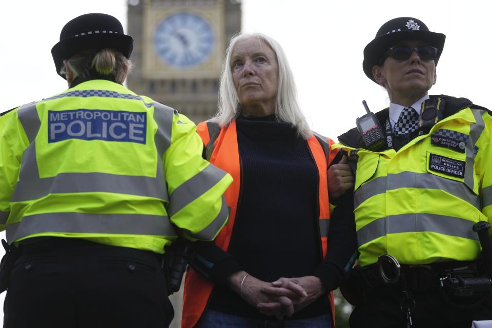 FILE- An activist from the group Just Stop Oil is arrested by police officers as they slow the traffic, marching on a road, in London, Monday, Oct. 30, 2023. Britain is one of the world's oldest democracies, but some worry that essential rights and freedoms are under threat. They point to restrictions on protest imposed by the Conservative government that have seen environmental activists jailed peaceful but disruptive actions. (AP Photo/Kin Cheung, File)