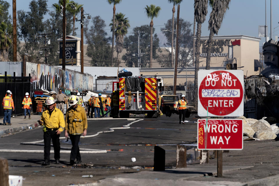 Los Angeles firefighters mop up damage from a fire that severely damaged a section of Interstate 10 in an industrial zone near downtown Los Angeles on Saturday, Nov. 11, 2023. Authorities say firefighters have mostly extinguished a large blaze that burned trailers, cars and other things in storage lots beneath a major highway near downtown Los Angeles, forcing the temporary closure of the roadway. (AP Photo/Richard Vogel)