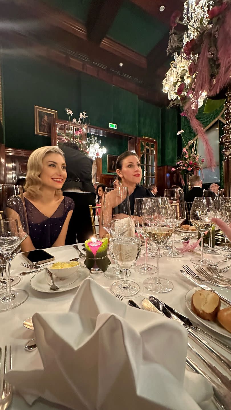 a couple of women sitting at a table with food and drinks