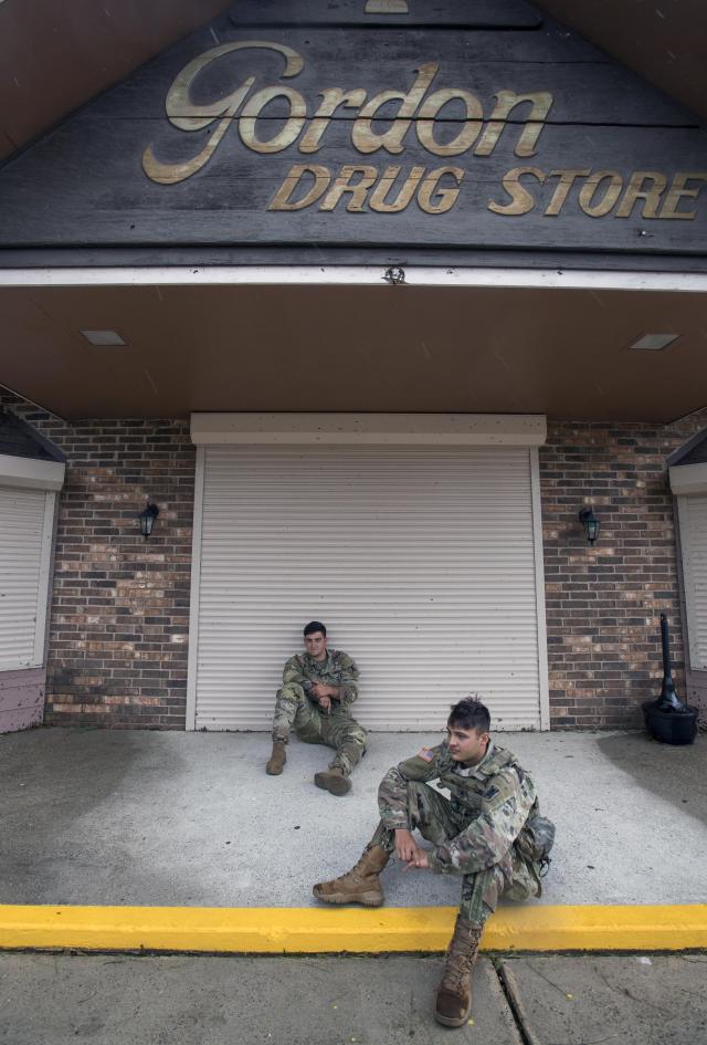 Louisiana National Guardsmen Sgt. Austin Hernandez, center, and Spc. Beau Scoggin, both of New Iberia, guard a drug store Friday, Aug. 28, 2020 in Lake Charles. Recovery efforts were underway after Hurricane Laura. (Chris Granger/The Times-Picayune/The New Orleans Advocate Via AP)