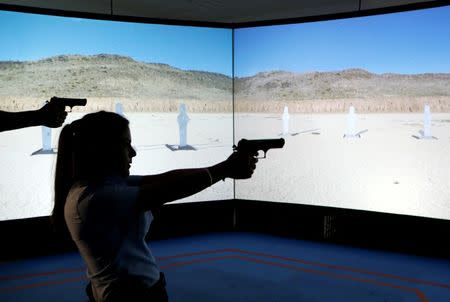 An Arab Israeli police recruit takes aim with her gun towards a screen displaying targets during a training exercise at Israeli police academy center in Beit Shemesh, Israel August 24, 2016. Picture taken August 24, 2016. REUTERS/Ammar Awad