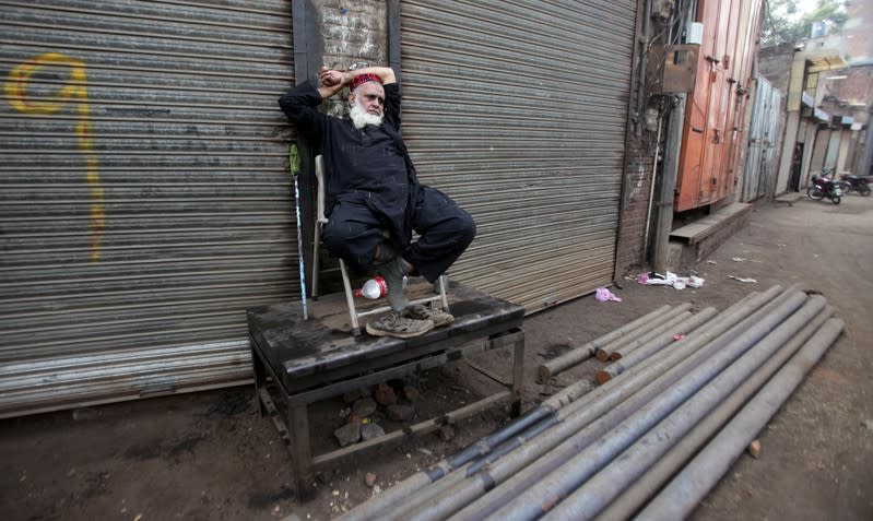 A worker sits outside closed shops during a country-wide lock down by the traders and business community, against what they say is imposition of taxes by the government in Lahore