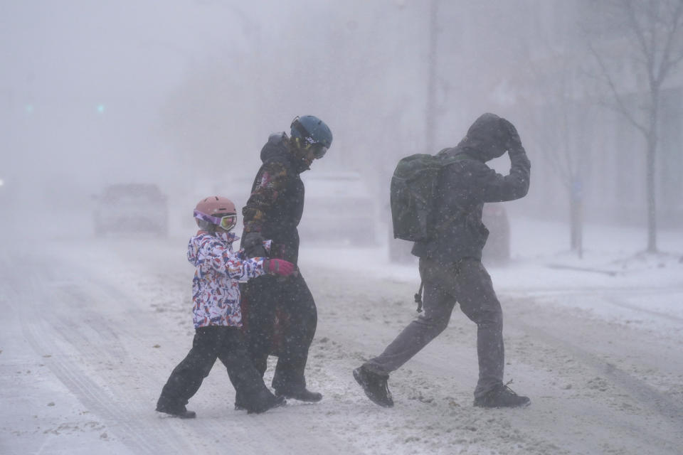 The Firestone family makes their way across Elmwood Avenue in Buffalo, N.Y. after stocking up on supplies at the grocery store, Friday, Dec. 23, 2022. Winter weather is blanketing the U.S. as a massive storm sent temperatures crashing and created whiteout conditions.(Derek Gee /The Buffalo News via AP)