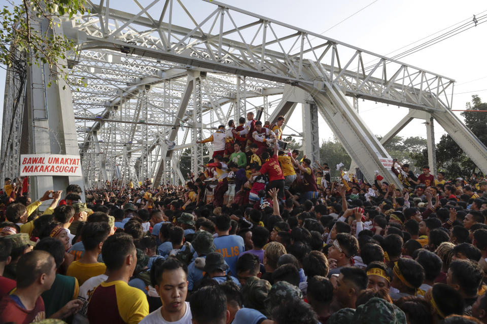A crowd of Filipino Roman Catholic devotees try to climb the carriage of the Black Nazarene during a raucous procession to celebrate its feast day Thursday, Jan. 9, 2020, in Manila, Philippines. A mammoth crowd of mostly barefoot Filipino Catholics prayed for peace in the increasingly volatile Middle East at the start Thursday of an annual procession of a centuries-old black statue of Jesus Christ in one of Asia's biggest religious events. (AP Photo/Aaron Favila)
