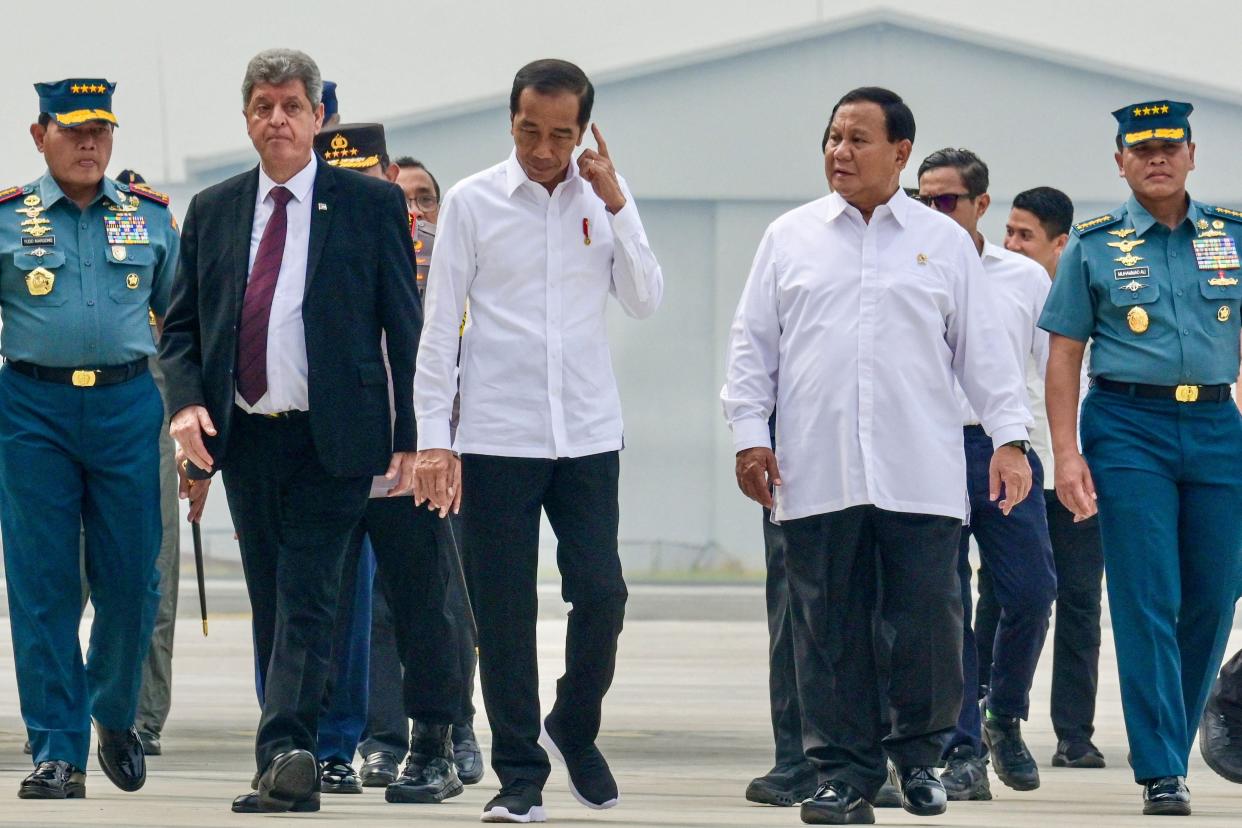 Indonesia’s president Joko Widodo gestures as he walks with Palestinian ambassador Zuhair Al Shun  and Defence Minister Prabowo Subianto at an air force base in Jakarta on 4 November 2023 (AFP via Getty Images)