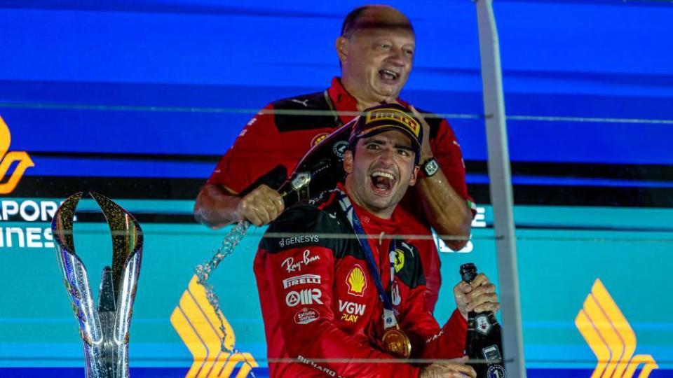 Carlos Sainz celebrates on the podium with Ferrari team principal Fred Vasseur after winning in Singapore 