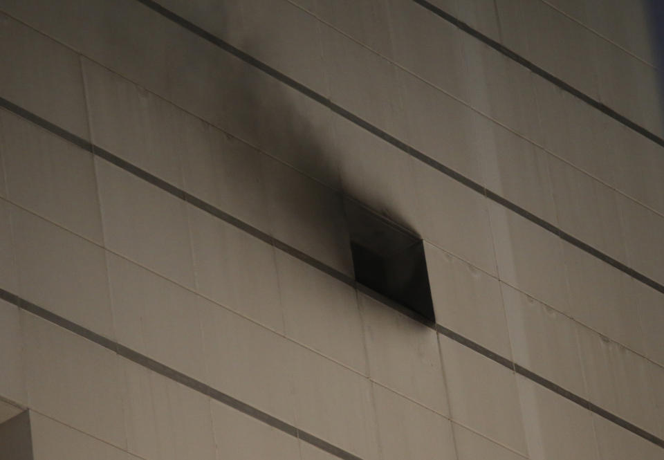 Smoke comes from an opening at the scene of a fire at the Central World mall complex in Bangkok, Thailand, Wednesday, April 10, 2019. A fire had broken out at the major mall complex in Thailand's capital, with initial reports from Thai emergency services saying it has caused numerous fatalities. (AP Photo/Sakchai Lalit)
