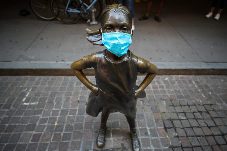 NEW YORK, USA - MAY 26: The Fearless Girl Statue with a face mask on which across the New York Stock Exchange (NYSE) building is seen during Covid-19 pandemic in Lower Manhattan, New York City, United States on May 26, 2020. Wall Street trading floor partially reopening after coronavirus pandemic shutdown. (Photo by Tayfun Coskun/Anadolu Agency via Getty Images)