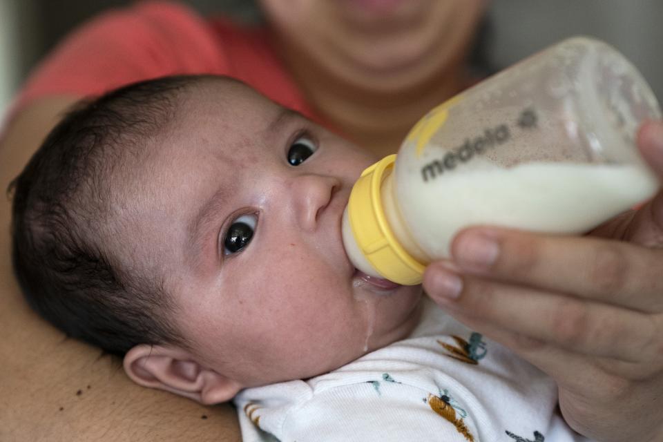 Two-month-old Ismael Galvaz is fed a bottle of formula by his mother, Yury Navas, 29, of Laurel, Md., from her dwindling supply of formula at their apartment in Laurel, Md., Monday, May 23, 2022. After this day's feedings she will be down to their last 12.5 ounce container of formula. Navas doesn't know why her breastmilk didn't come in for her third baby and has tried many brands of formula before finding the one kind that he could tolerate well, which she now says is practically impossible for her to find. To stretch her last can she will sometimes give the baby the water from cooking rice to sate his hunger. (AP Photo/Jacquelyn Martin)