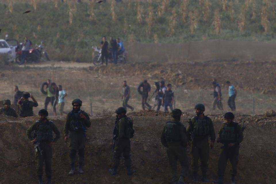 Israeli soldiers are positioned as Palestinian protesters arrive during a protest along the Israel Gaza border in Israel, Friday, Oct. 19, 2018. (AP Photo/Ariel Schalit)