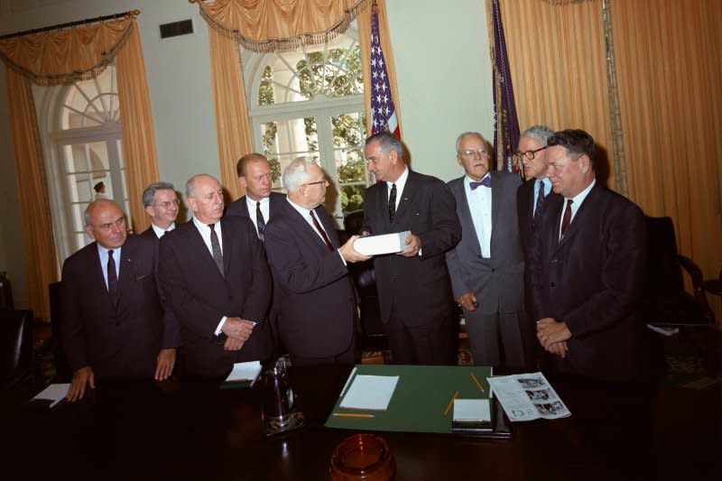 Members of the Warren Commission present their report on the assassination of President John F. Kennedy to President Lyndon B. Johnson on September 24, 1964. From L-R: John McCloy, J. Lee Rankin (general counsel), Sen. Richard Russell, Rep. Gerald Ford, Chief Justice Earl Warren, President Lyndon B. Johnson, Allen Dulles, Sen. John Sherman Cooper and Rep. Hale Boggs. File Photo by LBJ Library/UPI