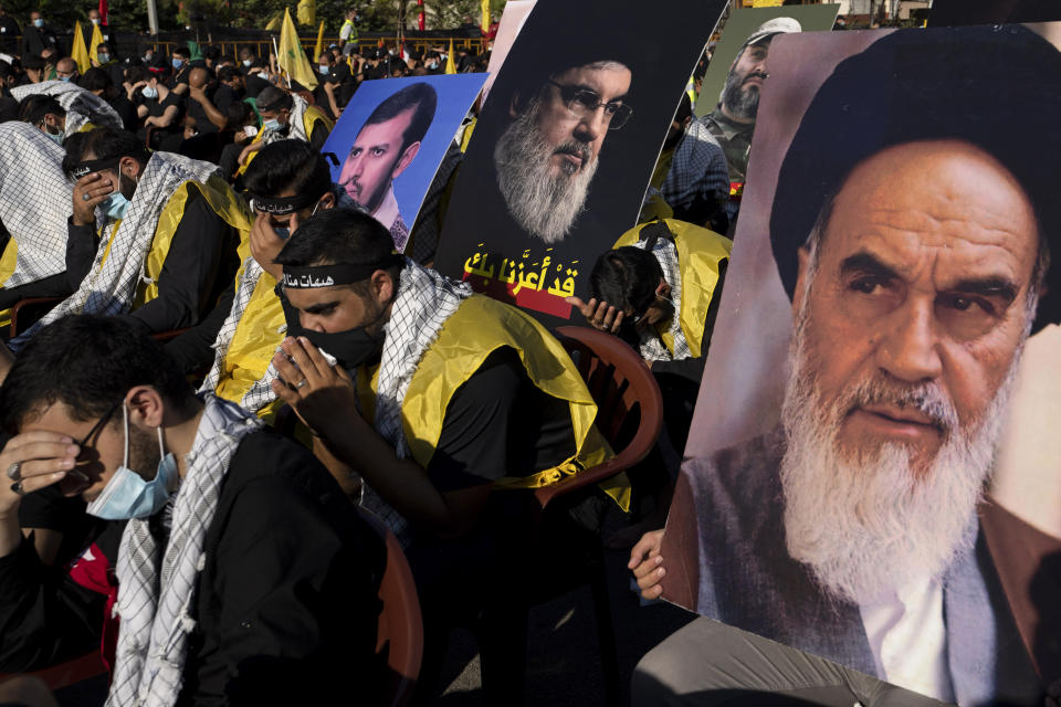 Hezbollah supporters hold up pictures of the late revolutionary founder Ayatollah Khomeini, right, Hezbollah leader Sayyed Hassan Nasrallah, center, and Abdel-Malek al-Houthi, the leader of Yemen's Shiite rebels, as they listen to the story of Ashoura, the Shiite Muslim commemoration marking the death of Immam Hussein, the grandson of the Prophet Muhammad, at the Battle of Karbala in present-day Iraq in the 7th century, in southern Beirut, Lebanon, Thursday, Aug. 19, 2021. The leader of the militant Hezbollah group Sayyed Hassan Nasrallah said Thursday that the first Iranian fuel tanker will sail toward Lebanon "within hours" warning Israel and the United States not to intercept it. (AP Photo/ Hassan Ammar)