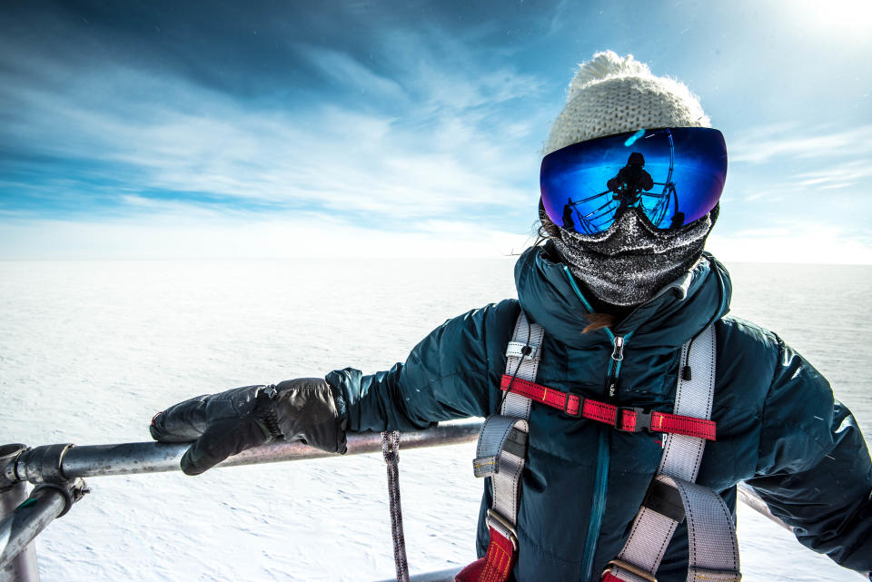 a person in protective gear poses for a portrait amidst a bare snowy landscape