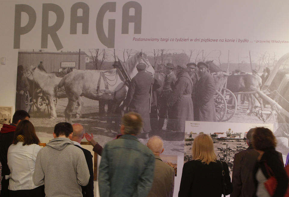 People watch a picture of the horse market in pre-World War II Warsaw’s Praga district, at a new exhibition by the Museum of the History of Polish Jews, in Warsaw, Poland, on Thursday, March 27, 2014. The exhibition that will run through June 30 documents Jewish life in Warsaw before the Holocaust. (AP Photo/Czarek Sokolowski)