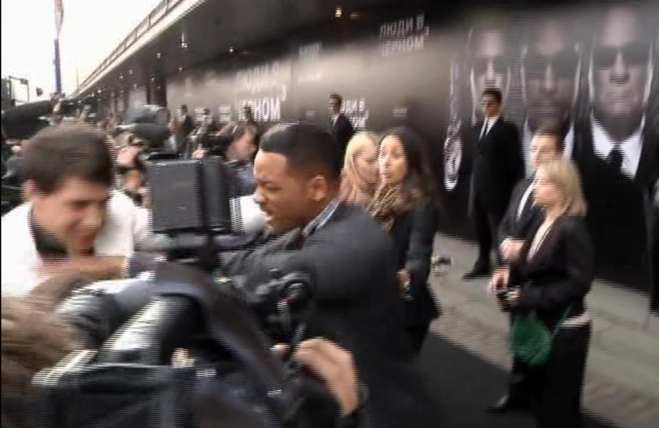 In this video image taken from AP video U.S. actor Will Smith, center, pushes reporter Vitalii Sediuk, white suit, from the Ukrainian television channel 1+1 on the red carpet before the premiere of "Men in Black III" Friday May 18, 2012 in Moscow. Hollywood star Will Smith has slapped a male television reporter who tried to kiss him before the Moscow premiere of "Men in Black III." Smith pushed him away and then slapped him lightly across the cheek with the back of his left hand. (AP Photo via AP video)