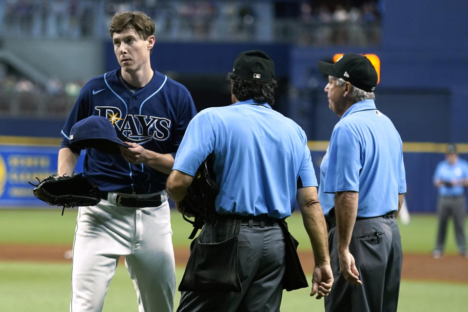 Tampa Bay Rays pitcher Ryan Yarbrough, left, walks off after being checked for foreign substances by umpires Phil Cuzzi, center, and Tom Hallion, right, after Yarbrough was taken out of the game against the Boston Red Sox during the third inning of a baseball game Tuesday, June 22, 2021, in St. Petersburg, Fla. (AP Photo/Chris O'Meara)