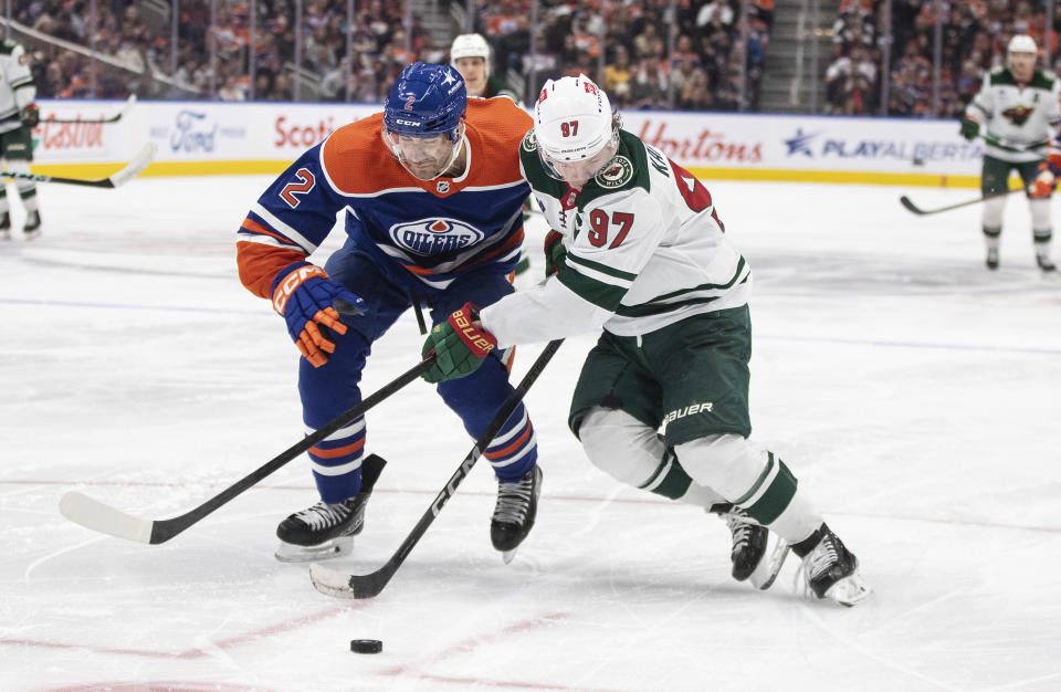 Minnesota Wild's Kirill Kaprizov (97) and Edmonton Oilers' Evan Bouchard (2) compete for the puck during the third period of an NHL hockey game Friday, Feb. 23, 2024, in Edmonton, Alberta. (Jason Franson/The Canadian Press via AP)