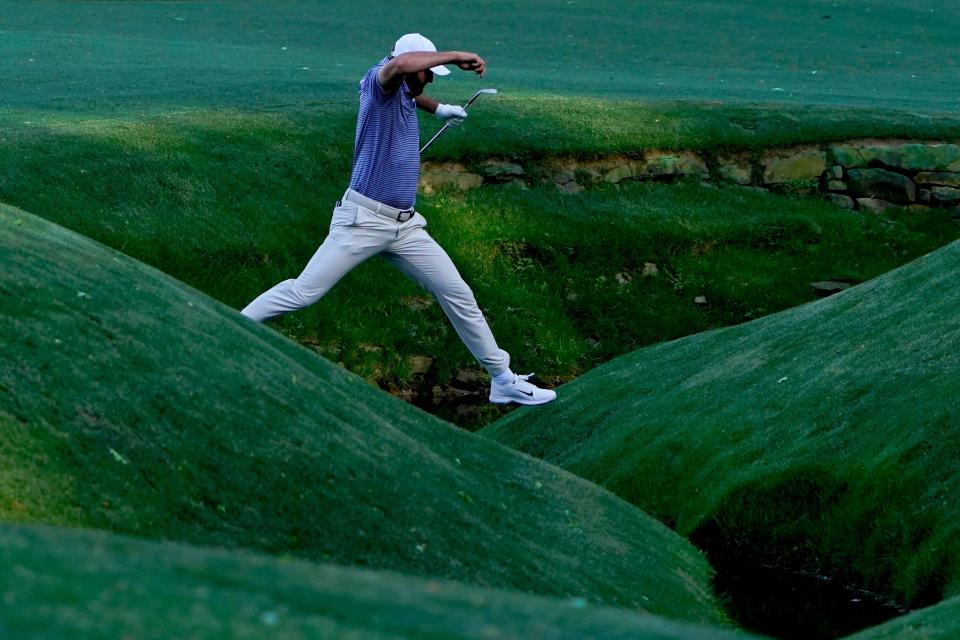 Scottie Scheffler jumps over Rae's Creek fronting the 13th green of the Augusta National Golf Club after hitting his second shot into the water during Friday's second round of the Masters Tournament. Scheffler is in a three-way tie for the lead with Bryson DeChambeau and Max Homa.