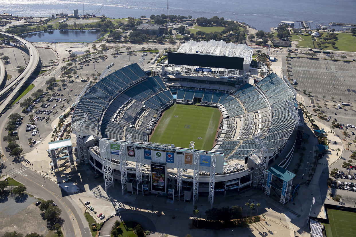 Aerial of an opened and empty field of Jacksonville Jaguars, TIAA Bank Field, Jacksonville, Florida on a sunny day, with the parking lot, highway, and river in the background