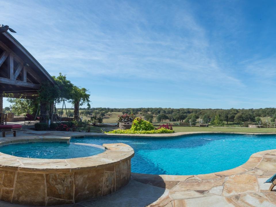 Terry Bradshaw's patio and pool looks out on a large yard of grass and trees.