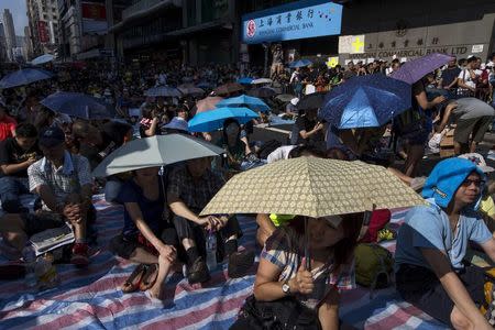 Protesters sit under umbrellas at a main street at Mongkok shopping district after thousand of protesters blocked the road in Hong Kong October 1, 2014. REUTERS/Tyrone Siu