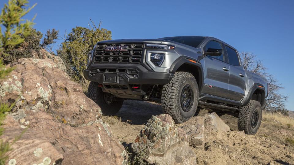 front 34 view of the 2024 gmc canyon at4x aev edition climbing a rock