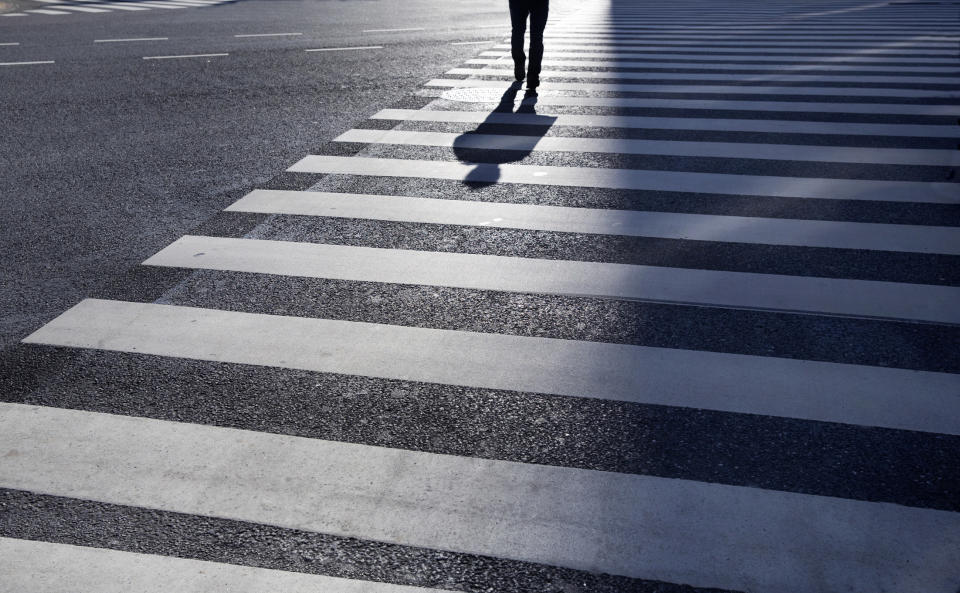 a crosswalk with a person's shadow