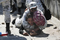 A Mexican National Guard detains a Central American migrant after he crossed the Suchiate River with a group of migrants from Guatemala into Mexico near Ciudad Hidalgo, Mexico, Monday, Jan. 20, 2020. More than a thousand Central American migrants hoping to reach the United States marooned in Guatemala are walking en masse across a river leading to Mexico in an attempt to convince authorities there to allow them passage through the country. (AP Photo/Marco Ugarte)