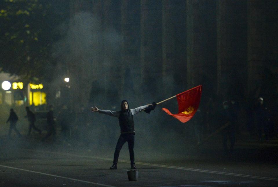 Protester waves a Kyrgyz flag during a rally against the results of a parliamentary vote in Bishkek, Kyrgyzstan, Monday, Oct. 5, 2020. Large crowds of people have gathered in the center of Kyrgyzstan's capital to protest against the results of a parliamentary election, early results of which gave the majority of seats to two parties with ties to the ruling elites amid allegations of vote buying. (AP Photo/Vladimir Voronin)