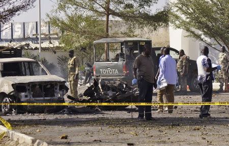 Bomb detection experts and members of the military stand at the scene of an explosion at a police station in Kano November 15, 2014. REUTERS/Stringer