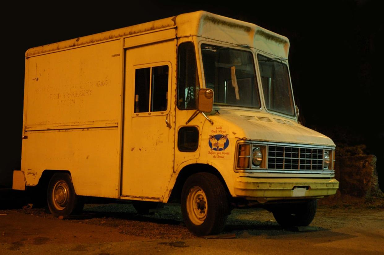 a creepy looking broken down ice cream truck under a bridge at night