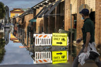 A pedestrian walks by a flooded Market St. as a king tide rolls into the popular tourist shopping area in Charleston, S.C. Sunday, Nov. 15, 2020. Charleston has remained relatively unscathed this hurricane season. That means more time to mull a $1.75 billion proposal by the Army Corps of Engineers that features a sea wall along the city's peninsula to protect it from deadly storm surge during hurricanes. (AP Photo/Mic Smith)