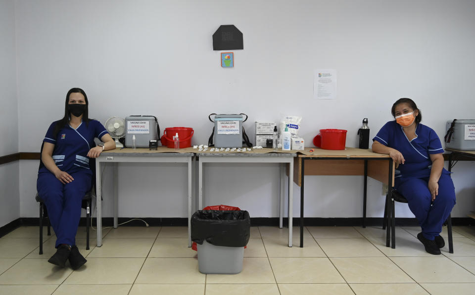 Health worker wait for people during a vaccination campaign in San Jose, Costa Rica, Tuesday, Jan. 18, 2022. (AP Photo/Carlos Gonzalez)