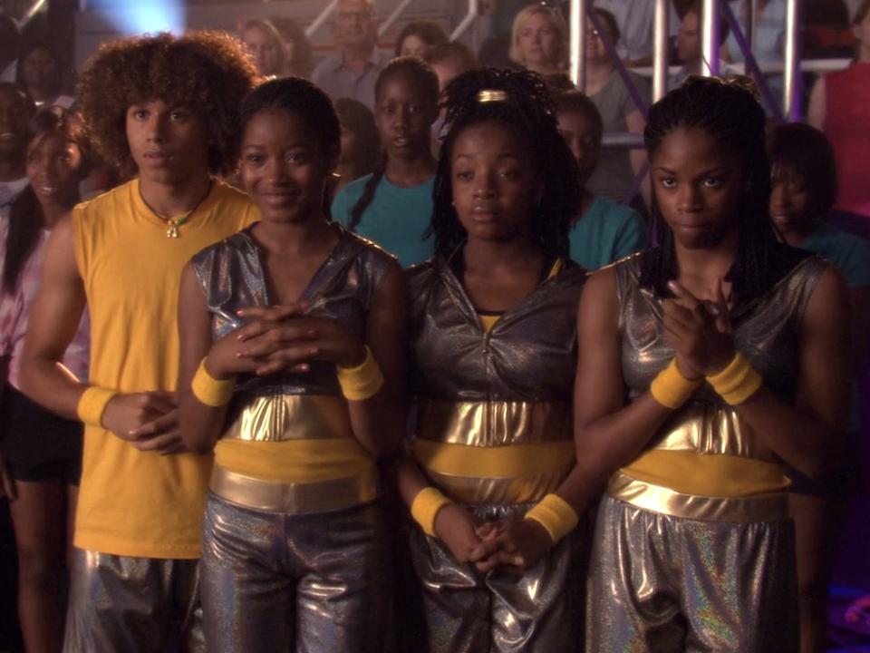 The cast of jump in wearing yellow and silver costumes