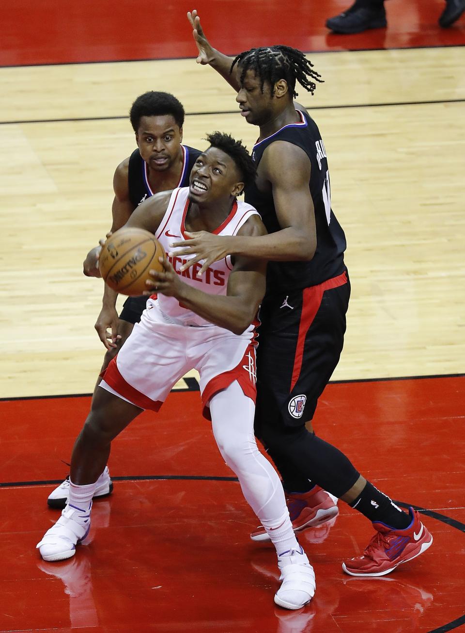 Houston Rockets' Jae'Sean Tate (8) is double-teamed by Los Angeles Clippers' Daniel Oturu, right, and Yogi Ferrell during the fourth quarter of an NBA basketball game Friday, May 14, 2021, in Houston. (Bob Levey/Pool Photo via AP)