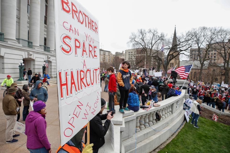 A person holds a sign demanding a haircut during a protest against the coronavirus shutdown in front of State Capitol in Madison, Wisconsin, on April 24, 2020. - Gyms, hair salons and tattoo parlors had a green light to reopen in the U.S. state of Georgia on Friday as the death toll from the coronavirus pandemic soared past 50,000 in the U.S. (Photo by KAMIL KRZACZYNSKI/AFP via Getty Images)