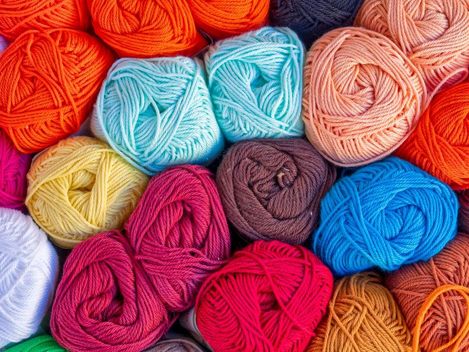 Several colorful bunches of yarn in red, blue, yellow and pink.