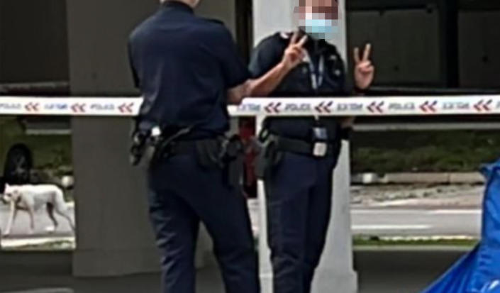 A police officer was seen posing with the 'V' sign near a blue tent. (PHOTO: Tracy Lim/Facebook)