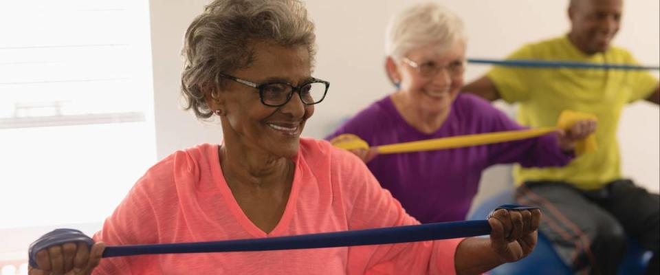 Front view of happy diverse senior woman exercising with resistance band in fitness studio