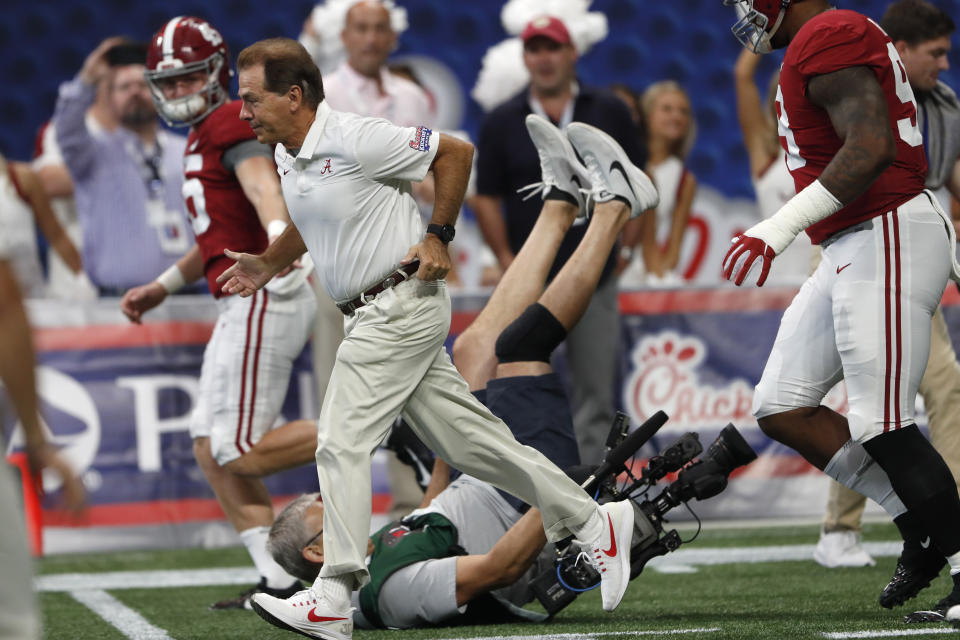 A cameraman falls as Alabama head coach Nick Saban leads his team onto the field to warm before an NCAA college football game against Duke Saturday, Aug. 31, 2019, in Atlanta. (AP Photo/John Bazemore)