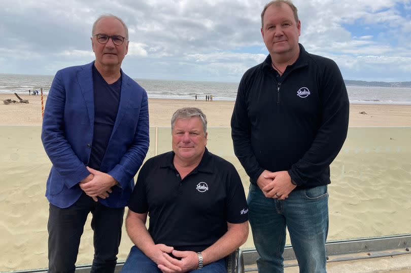 Three men pictured by a beach